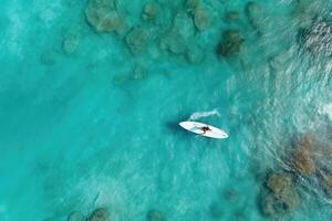 ai generado aéreo ver de un tablista con un tabla de surf en el mar, un aéreo ver de un mujer en un tabla de surf en el turquesa aguas de el Maldivas, ai generado foto