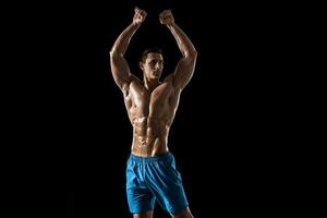 Muscular and fit young bodybuilder fitness male model posing over black background. photo