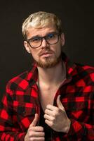 Image of attractive young bearded hipster man wearing glasses dressed in shirt in a cage isolated over black background. photo