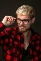 Image of attractive young bearded hipster man wearing glasses dressed in shirt in a cage isolated over black background. photo