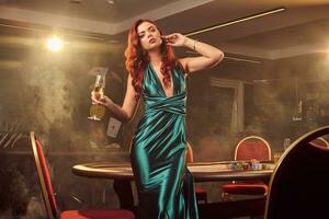 Young beautiful woman is posing against a poker table in luxury casino. photo