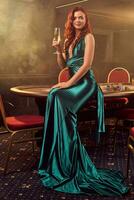 Young beautiful woman is posing against a poker table in luxury casino. photo