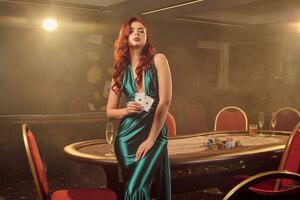 Young beautiful woman is posing against a poker table in luxury casino. photo