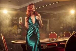 Young beautiful woman is posing against a poker table in luxury casino. photo