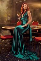 Young beautiful woman is posing against a poker table in luxury casino. photo