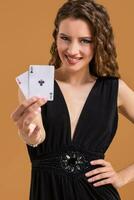 Beautiful brown-haired woman holding two aces as a sign for poker game, gambling and casino photo