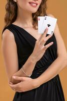 Beautiful brown-haired woman holding two aces as a sign for poker game, gambling and casino photo