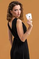 Beautiful brown-haired woman holding two aces as a sign for poker game, gambling and casino photo