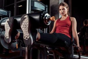 Woman exercising with crossover in fitness club or gym training legs photo