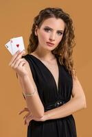 Beautiful brown-haired woman holding two aces as a sign for poker game, gambling and casino photo