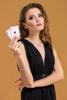 Beautiful brown-haired woman holding two aces as a sign for poker game, gambling and casino photo