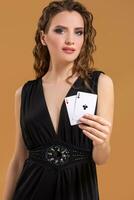 Beautiful brown-haired woman holding two aces as a sign for poker game, gambling and casino photo