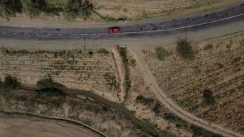The drone flies over a country road surrounded by steppe and bushes. Cars of different colors are driving along the road. video