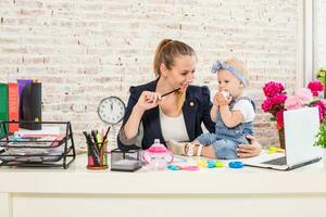 Mom and businesswoman working with laptop computer at home and playing with her baby girl. photo