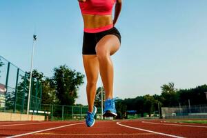 Runner jumping on the jogging track. Woman doing warm-up exercises before running. photo