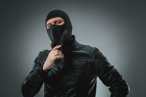 Robber with a gun, studio shot photo
