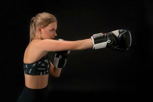 Beautiful female athlete in boxing gloves, in the studio on a black background. photo