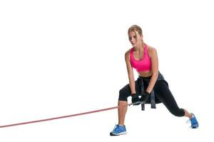 Strong woman using a resistance band in her exercise routine. Young woman performs fitness exercises on white background. photo