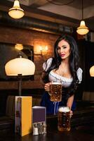 Beautiful female waitress wearing traditional dirndl and holding huge beers in a pub. photo