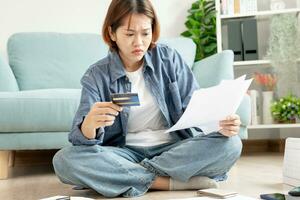 Stressed and headache asian woman with large bills or invoices no money to pay to expenses and credit card debt. shortage, Financial problems, mortgage, loan, bankruptcy, bankrupt, poor, empty wallet photo