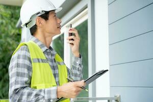 el inspector o ingeniero está inspeccionando la construcción y el aseguramiento de la calidad de la nueva casa usando una lista de verificación. ingenieros o arquitectos o contratistas trabajan para construir la casa antes de entregársela al propietario foto