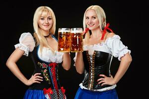 joven y hermosa bávaro muchachas con dos cerveza tazas en negro antecedentes foto
