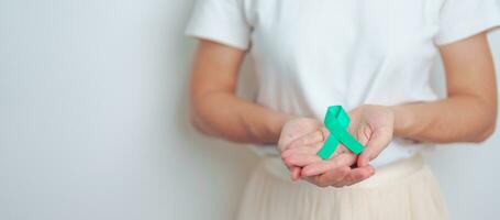 woman holding Teal Ribbon for January Cervical Cancer Awareness month. Uterus and Ovaries, Cervix, Endometriosis, Hysterectomy, Uterine fibroids, Reproductive, Healthcare and World cancer day photo