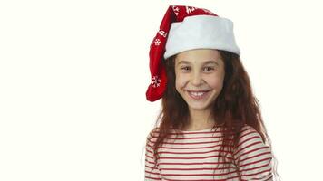 un niña en un Papa Noel claus gorra sonrisas a el cámara video