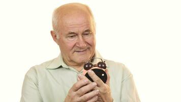 Old man looking at an alarm clock smiling to the camera video