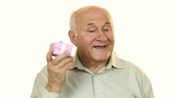 Happy grandpa smiling listening to a gift box guessing what is inside video