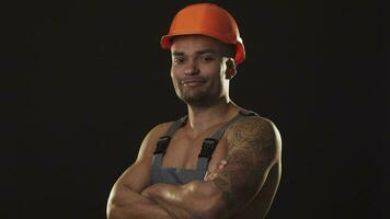 Happy muscular male builder in hardhat smiling showing thumbs up video