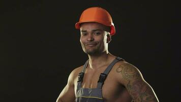 musclé Masculin constructeur dans vêtements de travail et casque fléchissement muscles video