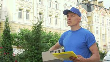 Delivery guy with cardboard box looking for the house of recepient client video