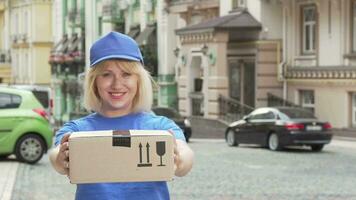 Cheerful delivery woman in blue uniform holding cardboard box video