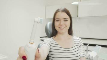 Selective focus on electric toothbrush in the hands of a happy woman video