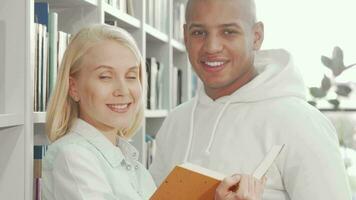 feliz multiétnico casal sorridente para a Câmera enquanto lendo uma livro video