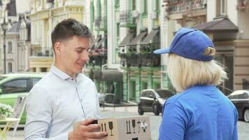 Handsome man examining package delivered by female courier video