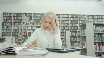 skön kvinna studerande stressande ut medan studerar på de bibliotek video