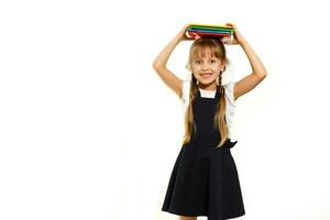 pequeño gracioso niña en camisa con libros. aislado en blanco antecedentes. bebé niña en escuela. el niño niña con libros de texto niña estudiando. foto