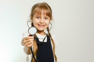 pequeño Chica de escuela estudios medicina con fonendoscopio, aislado en blanco foto