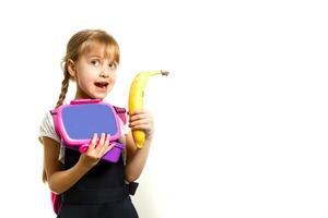 alumnos de primario colegio con loncheras en manos. muchachas con mochilas son comiendo fruta. comenzando de lecciones primero día de caer. foto