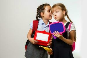 Two young girls whispering and sharing a secret during class in school photo