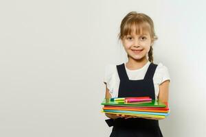 rubia Chica de escuela sostiene grande libro, disparar terminado blanco antecedentes foto