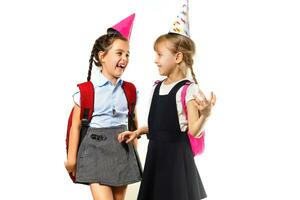 dos cumpleaños muchachas en camisa azul colegio uniforme vestidos sombrero aislado en blanco antecedentes niños estudio retrato. infancia niños educación estilo de vida concepto. burlarse de arriba Copiar espacio foto