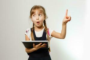 The little girl using the tablet on the white wall background photo