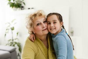 Portrait of happy old grandmother and kid girl looking at camera, smiling grandma with granddaughter making video call, child and granny vloggers recording video blog or vlog together photo