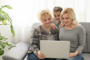 Grandmother and daughter teaching child use laptop application, playing game photo