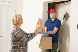 An elderly woman stays at home. Food delivery in a medical mask. photo