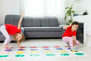 Two happy girls in children's clothes enthusiastically play on the floor. photo