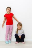 Two cute little girls in full growth, in the studio on a white background. The concept of a happy childhood, Beauty and fashion. Isolated. photo